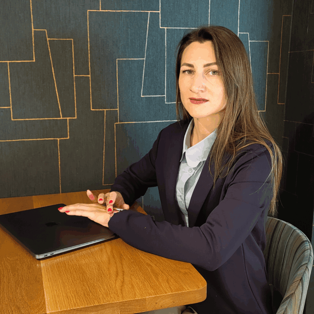 Model sitzt am Tisch mit Laptop