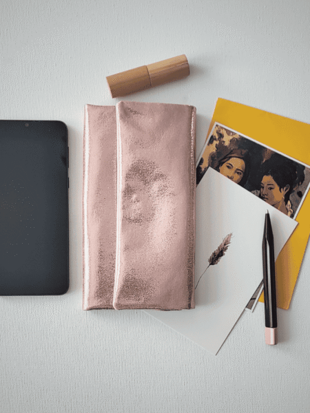 Flatlay Ansicht des Portemonnaies mit Handy, Karten, Stift und Lippenstift