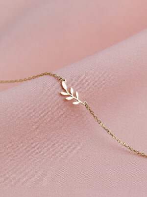 Armband aus 925 Sterlingsilber mit Blattzweig-Anhänger, Vermeil-vergoldet, auf rosa Stoff drapiert