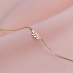 Armband aus 925 Sterlingsilber mit Blattzweig-Anhänger, Vermeil-vergoldet, auf rosa Stoff drapiert