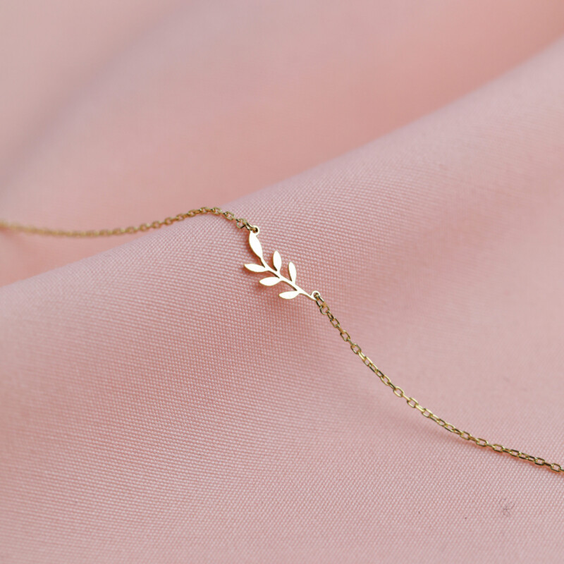 Armband aus 925 Sterlingsilber mit Blattzweig-Anhänger, Vermeil-vergoldet, auf rosa Stoff drapiert