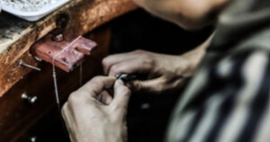 Ein Silberschmied fügt einzelne Schmuckkomponenten bei der Handfertigung von Silberschmuck zusammen